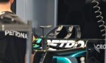 A cyclist in a dark jersey stands near high-end racing bikes mounted in a workshop setting.