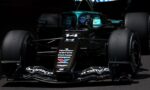 Front view of a teal-and-black Formula 1 car with sponsor logos, in a dark pit area, nose and cockpit visible.