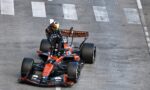 Top-down view of an orange Formula 1 car with a helmeted driver navigating a street circuit corner on a gray track with white markings.