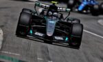 Mercedes Formula 1 car on track, close-up from the front-left, with Petronas sponsorship and rear wing visible as it speeds by.