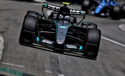Mercedes Formula 1 car on track, close-up from the front-left, with Petronas sponsorship and rear wing visible as it speeds by.