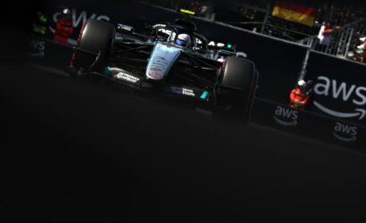 Front view of a Mercedes Formula 1 car speeding toward the camera on a dark race track, AWS branding in the background