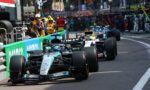 Formula 1 cars lined up in the pit lane with team members and equipment nearby, Mercedes-AMG Petronas livery visible.