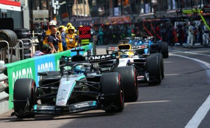 Formula 1 cars lined up in the pit lane with team members and equipment nearby, Mercedes-AMG Petronas livery visible.