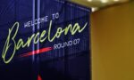 Blue banner reading 'Welcome to Barcelona' in lime-green cursive with 'WELCOME TO' in white and 'ROUND 07' at the bottom, indoors beside a yellow wall.