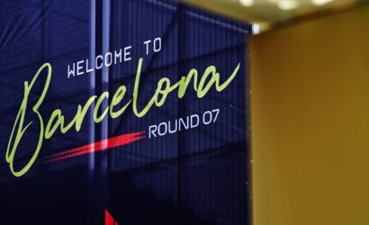 Blue banner reading 'Welcome to Barcelona' in lime-green cursive with 'WELCOME TO' in white and 'ROUND 07' at the bottom, indoors beside a yellow wall.