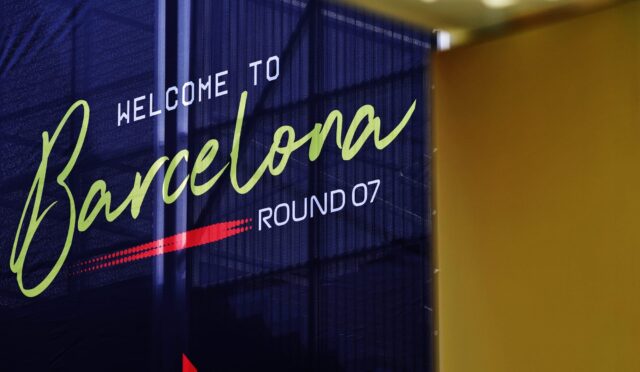 Blue banner reading 'Welcome to Barcelona' in lime-green cursive with 'WELCOME TO' in white and 'ROUND 07' at the bottom, indoors beside a yellow wall.