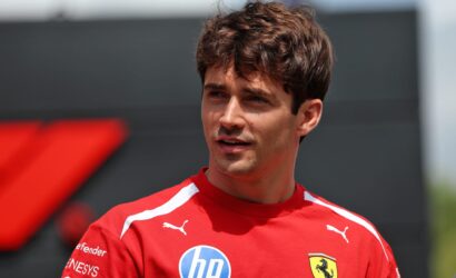 Portrait of a young man in a red athletic shirt with HP logo and Ferrari crest, outdoors in daylight.