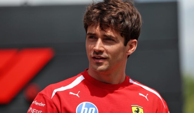 Portrait of a young man in a red athletic shirt with HP logo and Ferrari crest, outdoors in daylight.