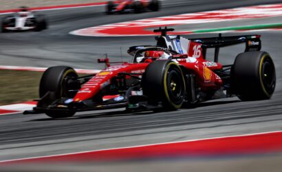 Ferrari Formula 1 car, number 16, in red livery, speeding around a curve on a race track with motion blur behind it.