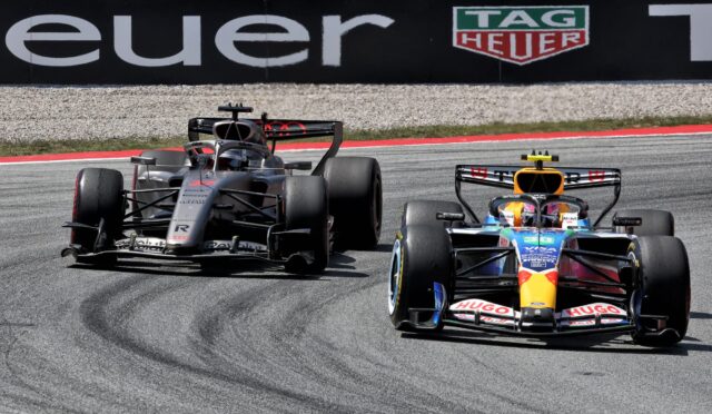 Two Formula 1 cars race side by side on a track near a wall with a TAG Heuer advertisement.