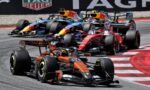 Close-packed Formula 1 race with several cars navigating a corner, colorful sponsor liveries and a TAG Heuer banner in the background.