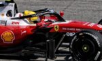 Ferrari Formula 1 car on track with driver in yellow helmet visible in the cockpit, front wing and red body covered in sponsor logos like Shell and ZYN