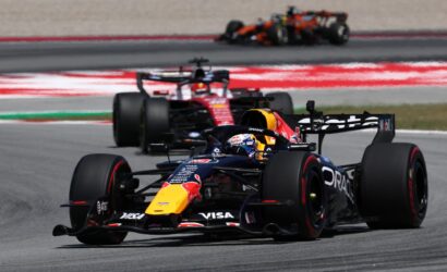 Red Bull Formula 1 car leads a high-speed race on a track, with other cars blurred in the background to show motion blur.
