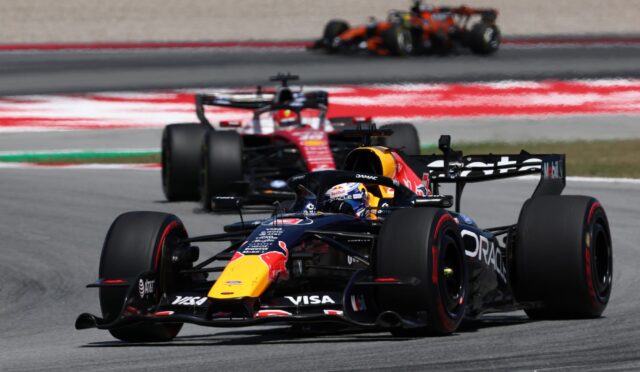 Red Bull Formula 1 car leads a high-speed race on a track, with other cars blurred in the background to show motion blur.