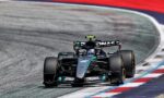 Mercedes-AMG Petronas Formula One car speeding through a corner on a race track with red, white, and blue curbs.