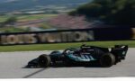 Mercedes-AMG Petronas Formula One car speeding along a race track with blurred grandstands in the background.