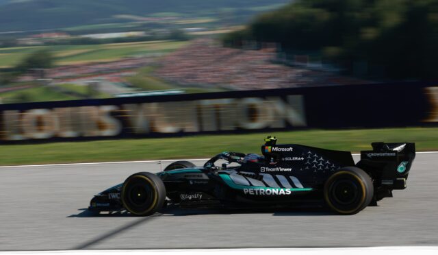 Mercedes-AMG Petronas Formula One car speeding along a race track with blurred grandstands in the background.