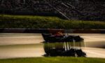 Formula 1 car with Red Bull livery racing along the track as grandstands full of spectators loom in the background.