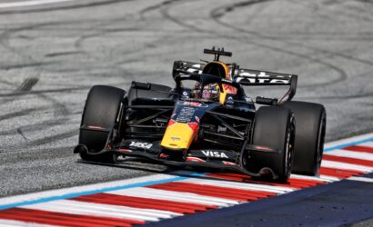 Race-ready Formula 1 car on a curving track, Red Bull livery, front wing down and tires smoking the tire marks in the asphalt background