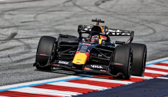 Race-ready Formula 1 car on a curving track, Red Bull livery, front wing down and tires smoking the tire marks in the asphalt background