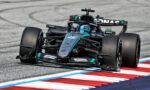 Mercedes-AMG Petronas Formula One car corners around the track, teal-black livery and prominent sponsor logos visible on the car and helmeted driver inside the cockpit.