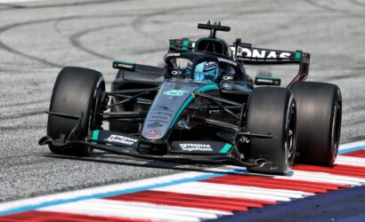 Mercedes-AMG Petronas Formula One car corners around the track, teal-black livery and prominent sponsor logos visible on the car and helmeted driver inside the cockpit.