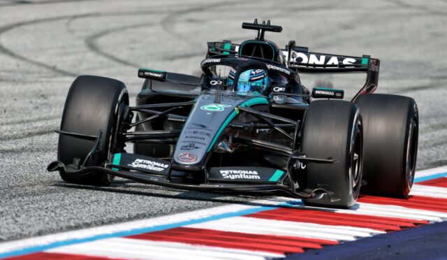 Mercedes-AMG Petronas Formula One car corners around the track, teal-black livery and prominent sponsor logos visible on the car and helmeted driver inside the cockpit.