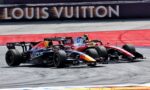 Two Formula 1 cars race side by side on a track, with a Louis Vuitton banner in the background, sponsor logos visible on the cars.