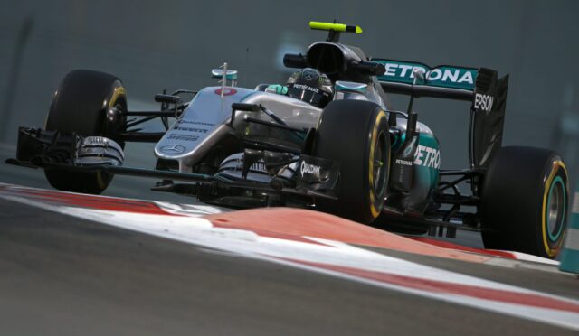 Silver Mercedes F1 car on a race track, close-up of the cockpit and front tires with PETRONAS branding in motion on a cornered bend.