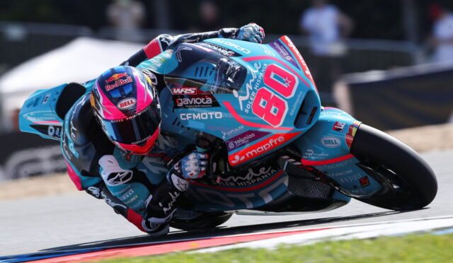 Motorcycle racer in teal-blue suit leaning into a sharp turn on a racetrack, bike number 68 with sponsor logos visible