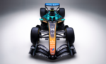 Front view of a teal-and-orange Formula 1 car with large rear wing and sponsor logos visible, facing the camera.