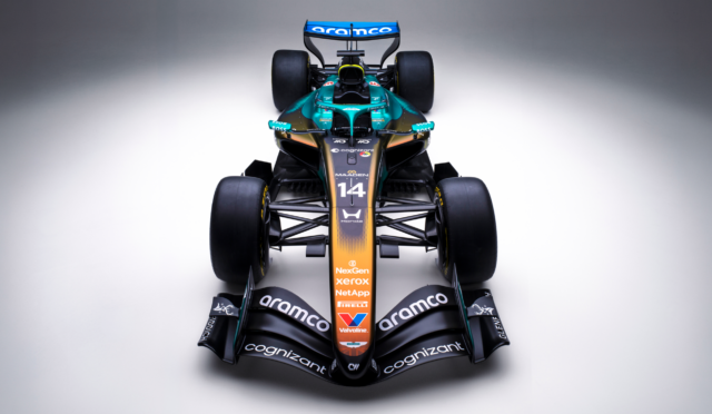 Front view of a teal-and-orange Formula 1 car with large rear wing and sponsor logos visible, facing the camera.