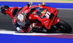 Rider on a red racing motorcycle leaning into a left turn on a track, number 31 visible.