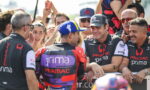 Pramac Racing team members congratulate a rider in a colorful racing suit as fans cheer in the background.