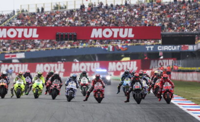 Motorcycle race start: riders in colorful suits accelerate from the grid as fans watch from grandstands under Motul banners.