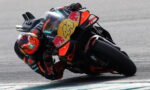 MotoGP rider in orange and black gear leaning into a turn on a Red Bull KTM race bike.