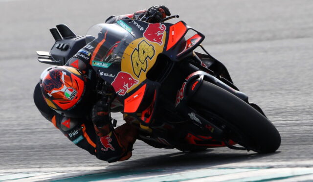 MotoGP rider in orange and black gear leaning into a turn on a Red Bull KTM race bike.