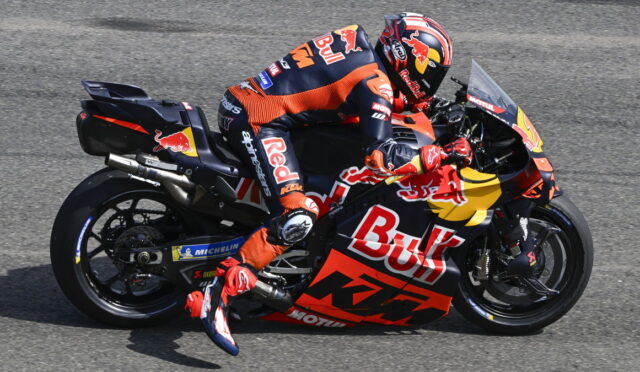MotoGP rider in Red Bull KTM livery leaning into a left turn on a race track, mid-corner.