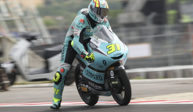Motorcycle racer in teal livery leans into a track turn on a racing bike number 31 with Leopard branding.