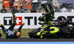 Moto racing crash: a rider in a neon-yellow suit leaps over a fallen bike as another rider sprawls on the track with spectators behind.”,“Rider in bright yellow-green gear hops over a crashed motorcycle during a race while a second rider lies on the asphalt.”,“On-track crash scene with a neon-yellow motorcycle racer mid-air and another rider on the ground, spectators in the background.”,“High-intensity racetrack crash: airborne rider in neon livery over a crashed bike as others watch from the barriers.”]}}{} | {