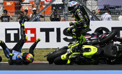 Moto racing crash: a rider in a neon-yellow suit leaps over a fallen bike as another rider sprawls on the track with spectators behind.”,“Rider in bright yellow-green gear hops over a crashed motorcycle during a race while a second rider lies on the asphalt.”,“On-track crash scene with a neon-yellow motorcycle racer mid-air and another rider on the ground, spectators in the background.”,“High-intensity racetrack crash: airborne rider in neon livery over a crashed bike as others watch from the barriers.”]}}{} | {