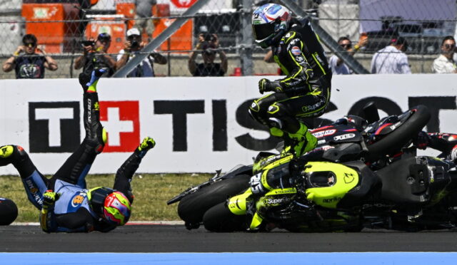 Moto racing crash: a rider in a neon-yellow suit leaps over a fallen bike as another rider sprawls on the track with spectators behind.”,“Rider in bright yellow-green gear hops over a crashed motorcycle during a race while a second rider lies on the asphalt.”,“On-track crash scene with a neon-yellow motorcycle racer mid-air and another rider on the ground, spectators in the background.”,“High-intensity racetrack crash: airborne rider in neon livery over a crashed bike as others watch from the barriers.”]}}{} | {