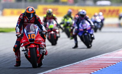 Motorcycle racer number 10 leads a pack on a race track with riders blurred in the background on a curve.