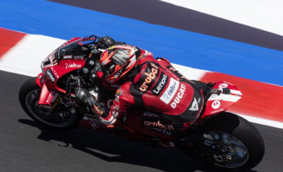 MotoGP rider in red Ducati gear leaning into a corner on the racetrack.