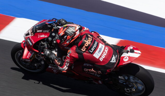 MotoGP rider in red Ducati gear leaning into a corner on the racetrack.