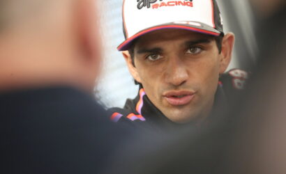 Close-up of a man in an Aprilia Racing cap speaking during an interview.