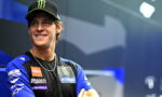 Smiling male motorcycle racer in a blue Yamaha team jersey and black Monster Energy cap.