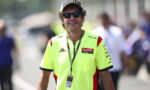 Man wearing a neon yellow Enduro team shirt, black sunglasses, and a cap with Monster logo at an outdoor event; lanyard with badge hanging from neck.