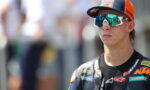 Male motorcycle racer wearing a Red Bull KTM cap and mirrored sunglasses, looking ahead in a racing suit with sponsor logos
